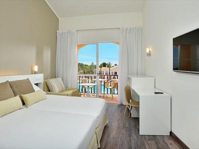Modernes Hotelzimmer mit Doppelbett, Schreibtisch, Fernseher und Balkon mit Meerblick.
