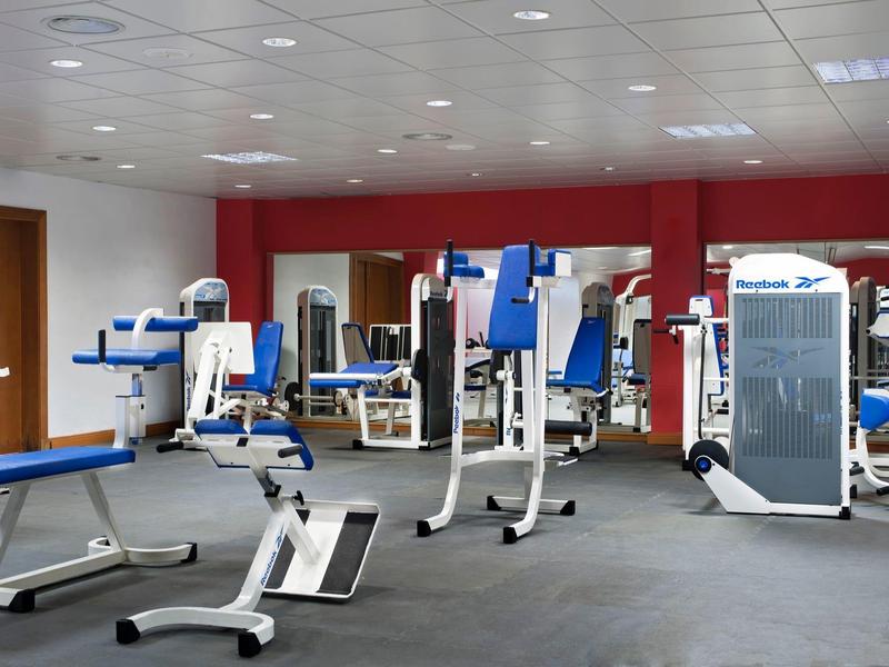 Velká posilovna s různými tréninkovými stroji a zrcadlovými stěnami.