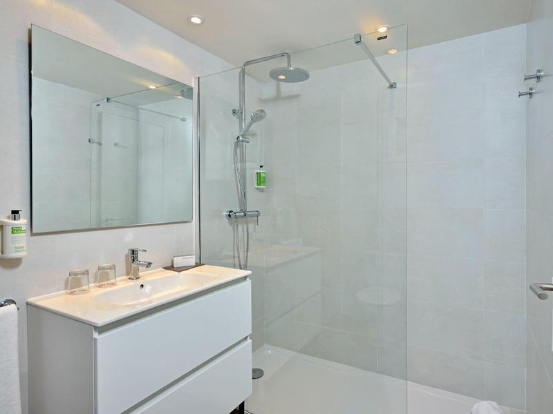 Moderní bílá koupelna s umyvadlem a sprchou s prosklenou stěnou