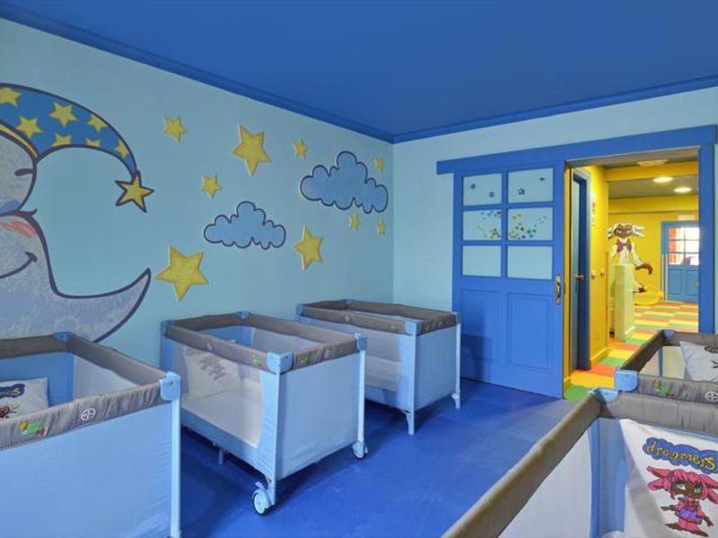 Světle modrá místnost s postýlkami a nástěnnou malbou měsíce, vhodná pro děti v hotelech.