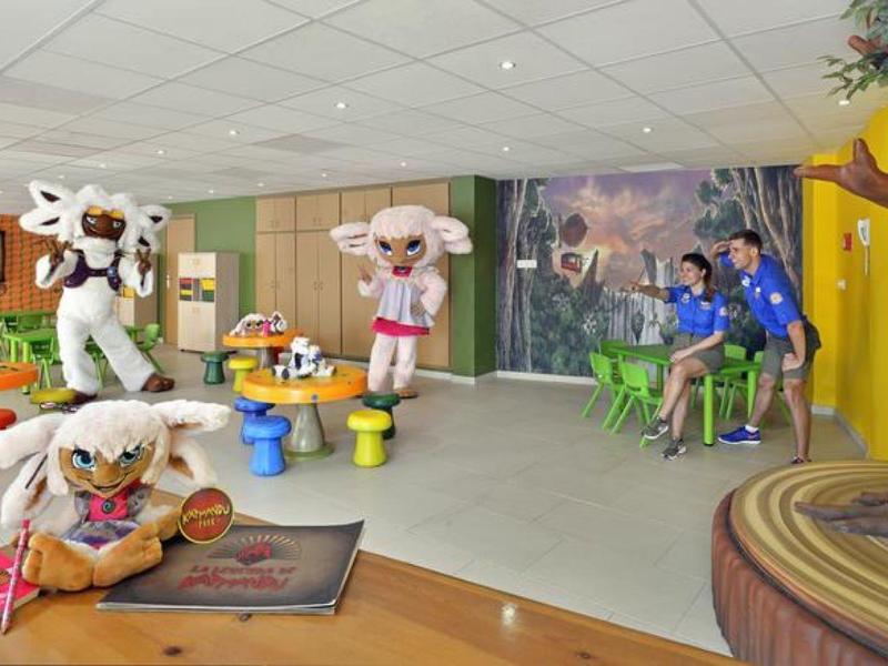 Dětská zóna s kostýmy zvířat, barevným nábytkem a aktivitami v světlé místnosti.