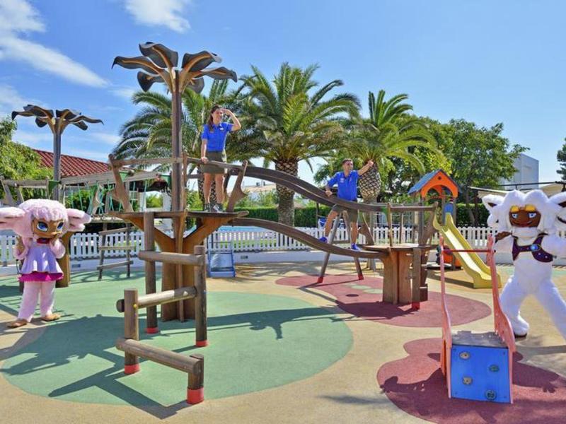 Barevné dětské hřiště s lezeckými konstrukcemi a postavami pod modrou oblohou.