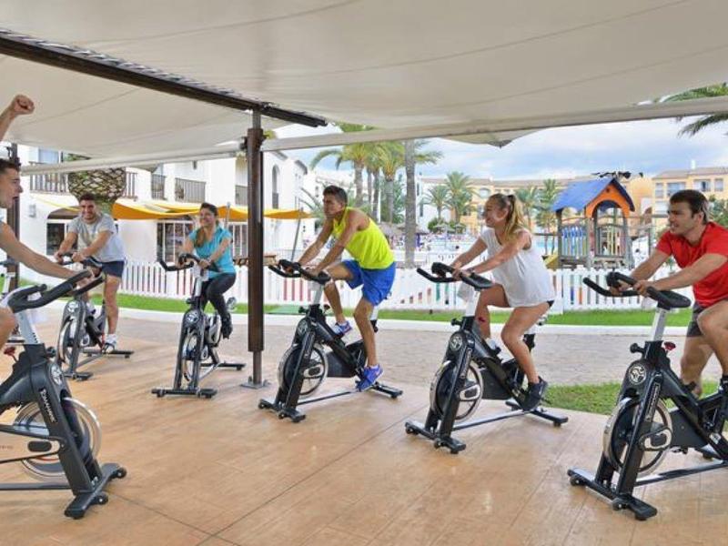 Skupina lidí na stacionárních kolech v kryté venkovní části hotelu.