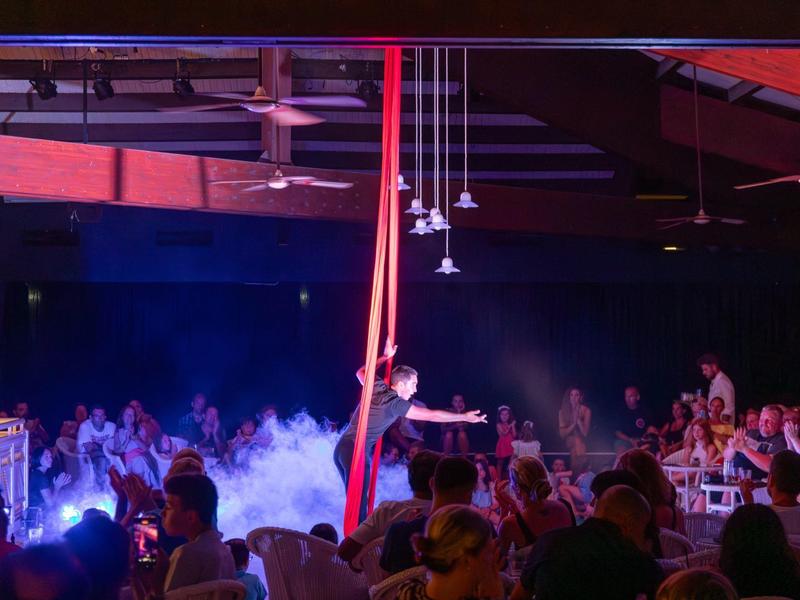 Lidé sedí v tmavém klubu s mlhou a červeným osvětlením.