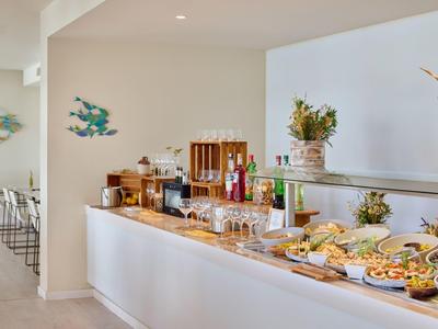 Buffet met drankjes, glazen en diverse snacks in een moderne hotelomgeving.