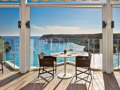 Balkon met tafel en stoelen met uitzicht op zee en kliffen op een zonnige dag.