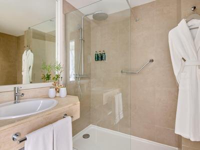 Moderne badkamer met inloopdouche, handdoeken en badjas in beige tinten.