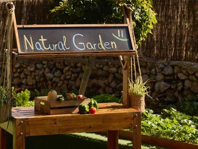 Houten tafel in de tuin met fruit, groenten en een bord met de tekst Natural Garden