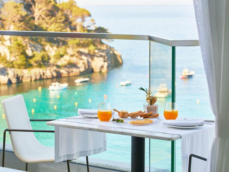 Tafel met ontbijt op balkon met uitzicht op zee en kliffen.