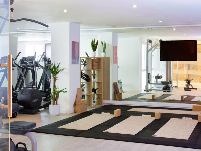 Moderne fitnessruimte met loopbanden, gewichten en grote spiegels in een lichte omgeving.