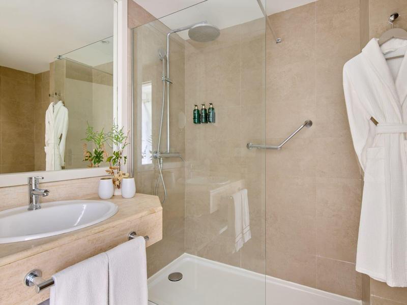 Moderne badkamer met inloopdouche, handdoeken en badjas in beige tinten.