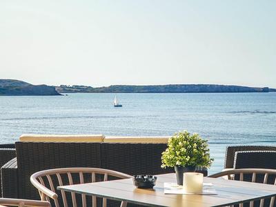 Una mesa con velas y sillas con vista al mar y a islas distantes.