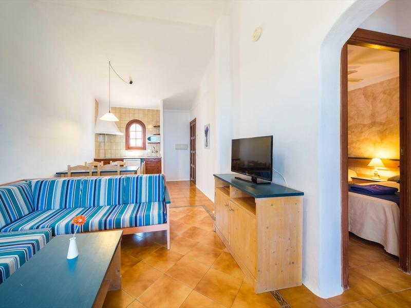 Sala moderna con sofá de rayas azules, televisor y dormitorio contiguo.