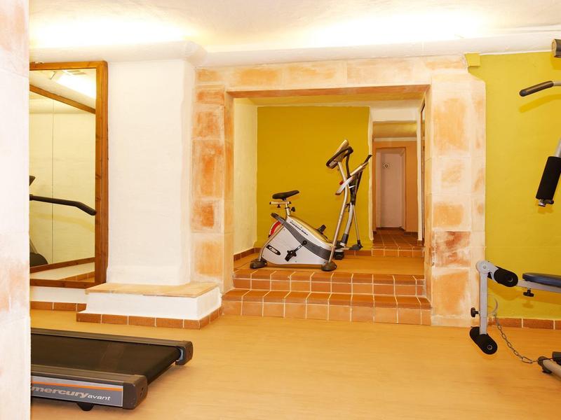Sala de fitness con cinta de correr, bicicleta estática y equipo multifuncional en un espacio luminoso.