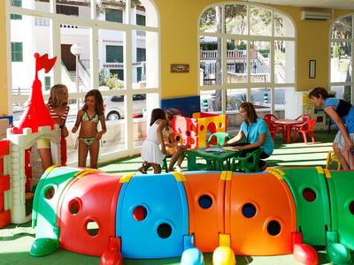 Kinder spielen in einem hellen, farbenfrohen Innenbereich mit Spielzeug und großen Bauklötzen.
