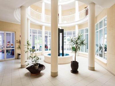 Helle Hotellobby mit Säulen, großen Fenstern und Topfpflanzen.