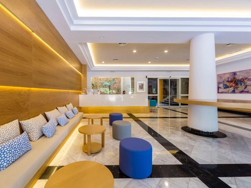 Heller, moderner Hotel-Lobbybereich mit Sitzgelegenheiten und Holzverkleidung an der Wand.