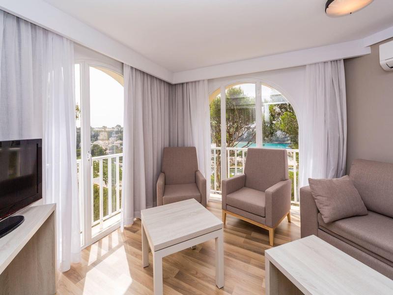 Helles Wohnzimmer mit Sitzbereich, Balkon und Stadtblick in warmen Tönen.