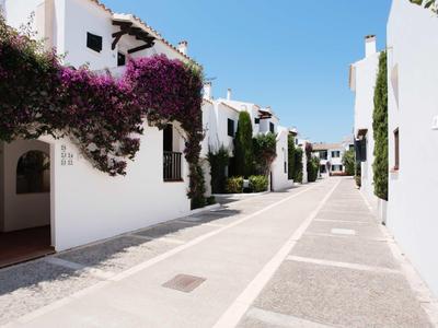 Rue lumineuse avec des bâtiments blancs et des fleurs dans une station balnéaire ensoleillée