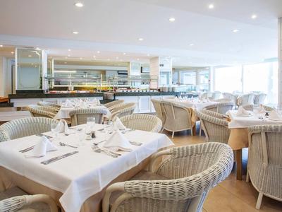 Restaurant lumineux et moderne avec nappes blanches et chaises tressées dans un hôtel.