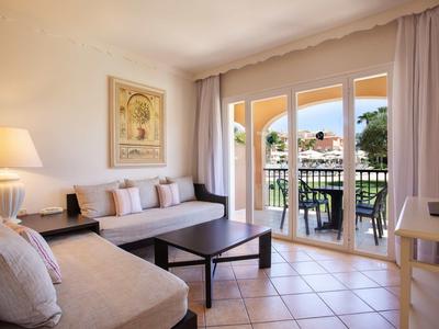 Sala luminosa con sofá, mesa de centro y acceso a balcón con vista al paisaje.