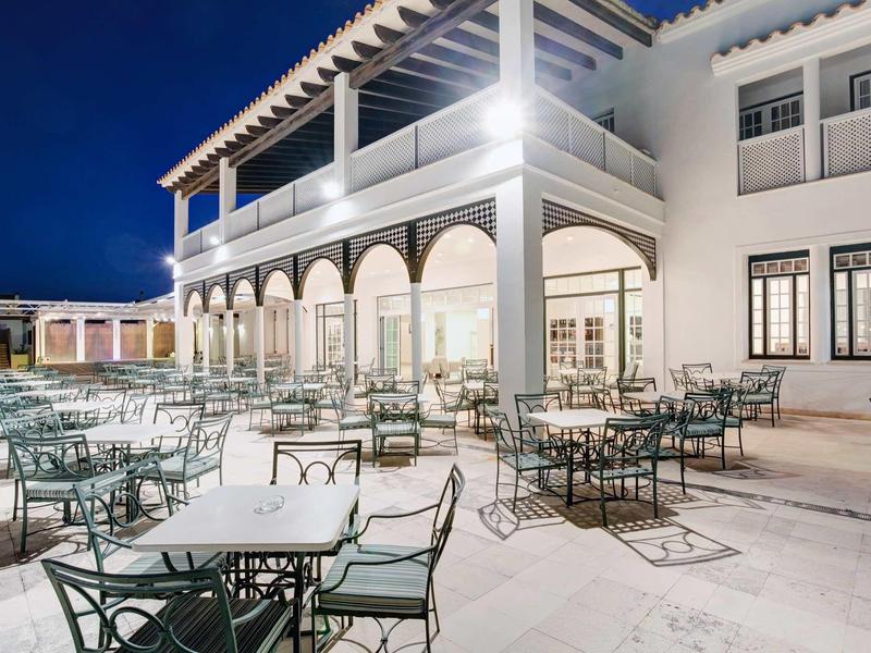 Terrasse d'hôtel illuminée avec tables et chaises la nuit