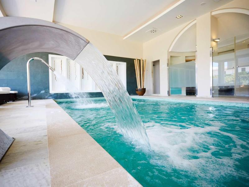 Piscine intérieure avec jet d'eau dans un espace bien-être moderne