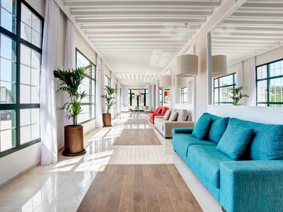 Heller, moderner Wohnraum mit großem Fenster, blauem Sofa und Pflanzen.