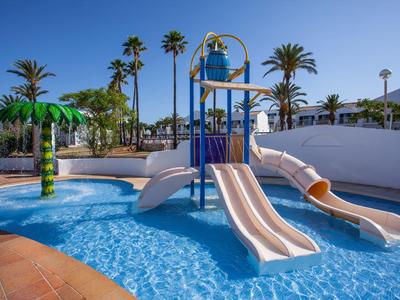 Dziecięcy park wodny z zjeżdżalniami, brodzikiem i palmami pod niebieskim niebem