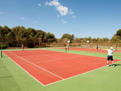 Buiten tennisbaan met twee spelers en groene omgeving onder een blauwe lucht.