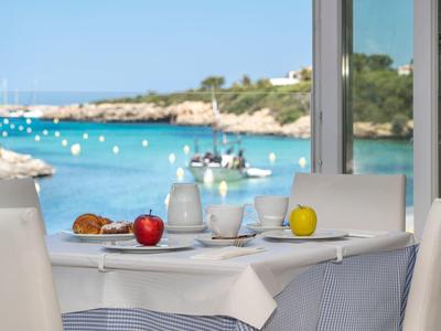 Stół w restauracji z widokiem na niebieskie morze i linię brzegową z żaglówkami.