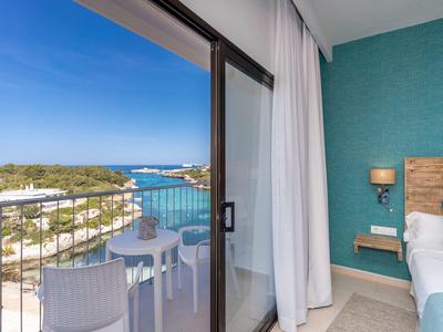 Balkon z widokiem na nadmorski krajobraz i morze w pokoju hotelowym z niebiesko-zieloną ścianą.