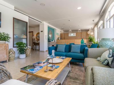 Sala d'attesa moderna e accogliente con divani e tavolo in uno spazio luminoso e aperto.