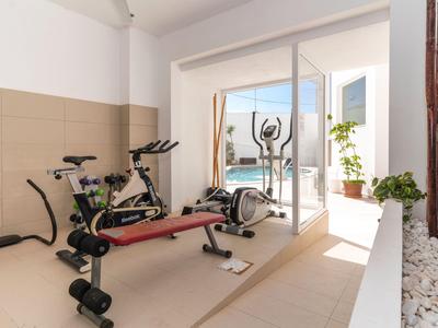 Palestra luminosa con attrezzature moderne e vista attraverso una porta a vetri su un'area esterna.