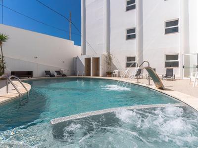 Nowoczesny basen na zewnątrz i jacuzzi z białymi ścianami oraz krzesłami w hotelu.