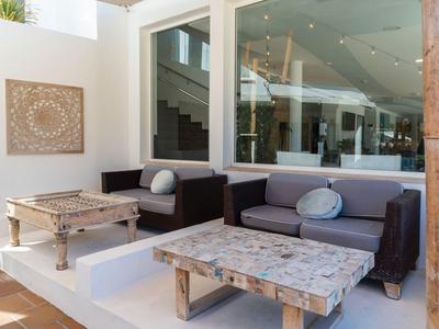 Elegancki taras z wygodnymi sofami, stołami i nowoczesną architekturą w tle.