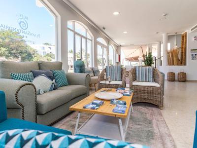 Jasna strefa wypoczynkowa w hotelu z sofami, fotelami, stolikiem kawowym i dużymi oknami z widokiem na zewnątrz.