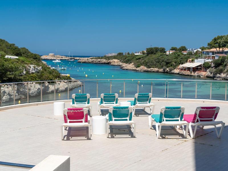 Widok na taras z kolorowymi leżakami i widokiem na morze pod czystym niebem.