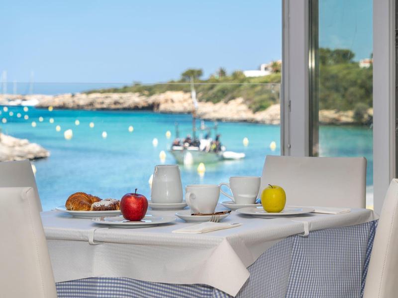 Stół w restauracji z widokiem na niebieskie morze i linię brzegową z żaglówkami.