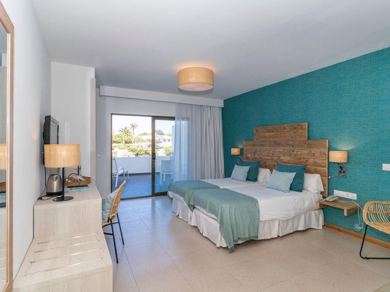 Nowoczesny pokój hotelowy z podwójnym łóżkiem, biurkiem i balkonem z widokiem na morze.