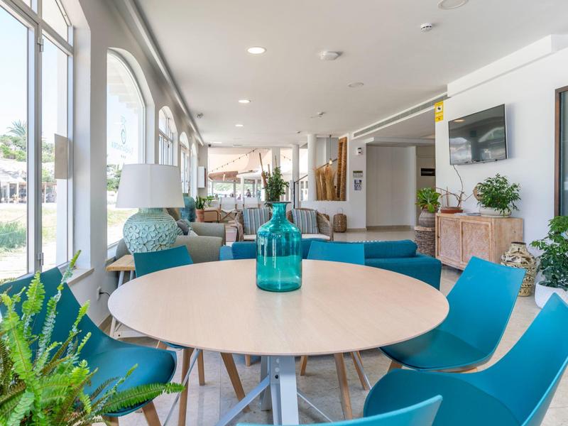 Jasna nowoczesna jadalnia z okrągłym stołem, niebieskimi krzesłami i dużymi oknami z widokiem na zewnątrz.