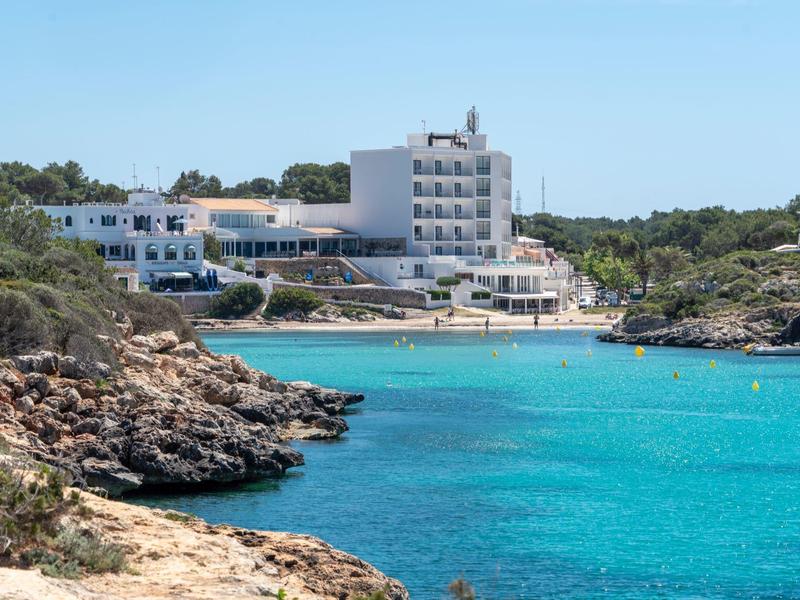 Budynek hotelu przy wybrzeżu z czystą turkusową wodą i skalistym brzegiem