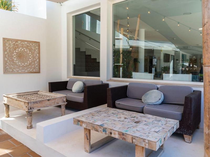 Elegancki taras z wygodnymi sofami, stołami i nowoczesną architekturą w tle.