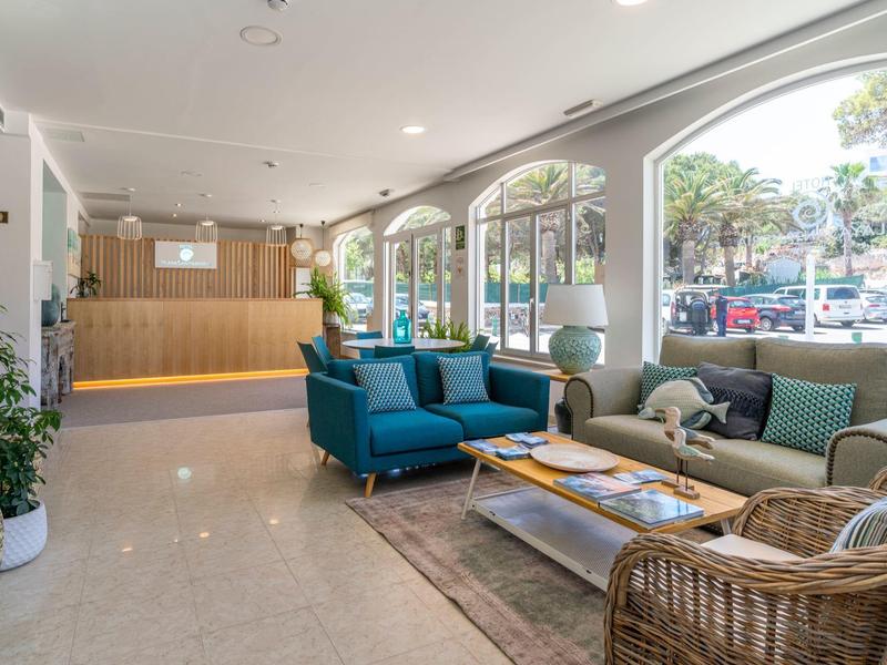 Jasna lobby hotelowa z wygodnymi miejscami do siedzenia, dużymi oknami i nowoczesnym wystrojem.