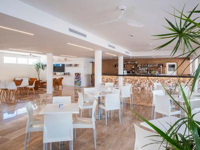 Helles, modernes Restaurant mit weißen Stühlen, Holztischen und Pflanzenakzenten.