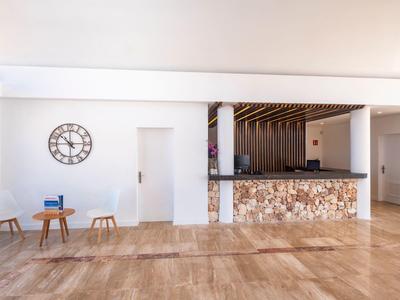 Area reception moderna dell'hotel con bancone rivestito in pietra e pareti bianche