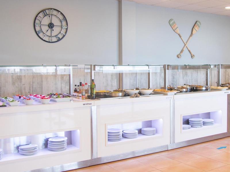 Buffet in una stanza luminosa con piatti ed elementi decorativi sulla parete.