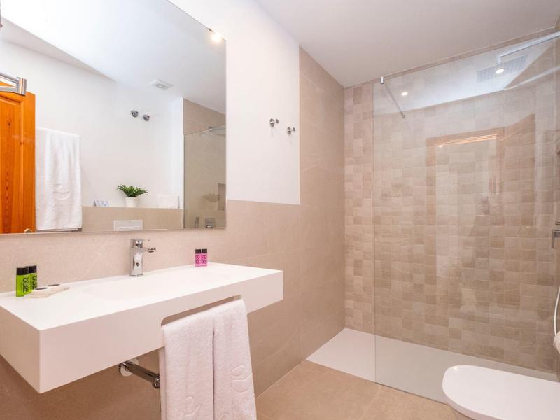 Bagno moderno con lavabo, specchio, doccia e asciugamani.