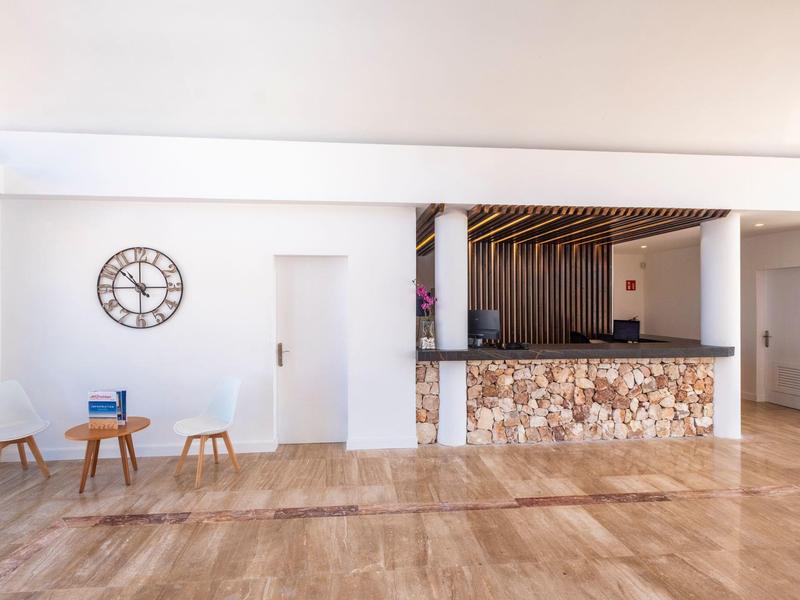 Area reception moderna dell'hotel con bancone rivestito in pietra e pareti bianche