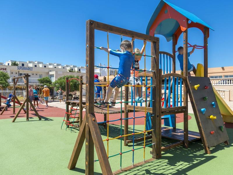 Bambini che giocano su una struttura da arrampicata in un parco giochi all'aperto con cielo sereno.